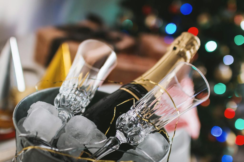 selective focus photography of brown labeled bottle and two clear glass champagne flutes